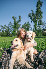 Girl with two golden retriever dogs in a park