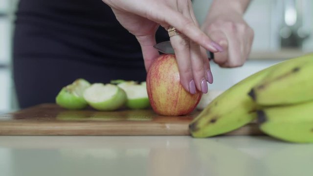 Close view of female hands cuts apples on kitchen