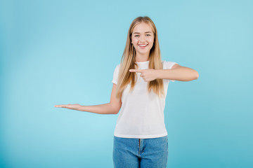 smiling happy woman pointing finger at copyspace on hand isolated over blue