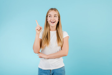 happy blonde woman having idea pointing finger up isolated over blue