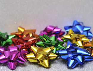 Festive colorful bows on sparkling glitter paper texture. Holiday background. Christmas concept.