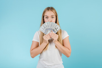 happy young blonde girl with dollar money in her hand isolated over blue