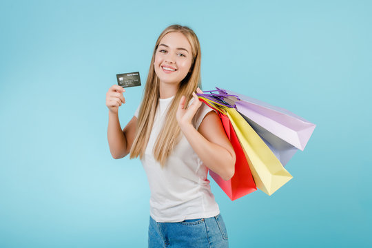 pretty young woman with credit card and colorful shopping bags isolated over blue