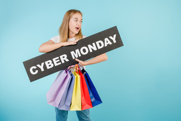 happy woman with cyber monday sign and colorful shopping bags isolated over blue