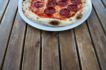 Rosy pepperoni pizza on a wooden table, smelling odorlessly.