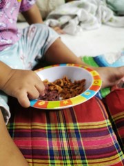 hands​ of​ little​ baby​  holding crispy​ bacon​ to​ eat from the bowl in the family house in the morning