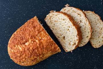 Sliced loaf of garlic parmesan bread on a black plastic cutting board