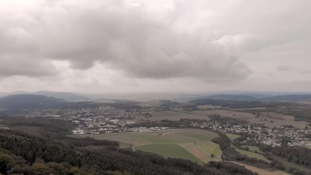 Aerial tilt from the top of the Wilzenberg pilgrimage mountain in the Sauerland region in Germany with wide view of the countryside on an overcast day