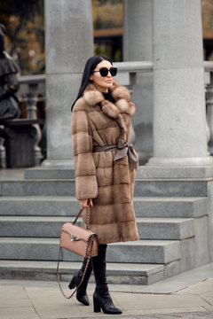 Fashion woman walks around the city. a coat with fur on it. Set of warm clothes
