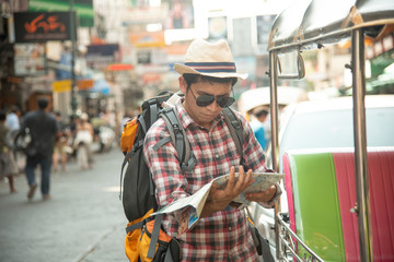  An Asian male tourist is watching a plan on the road,  Khao San Road, a popular tourist destination