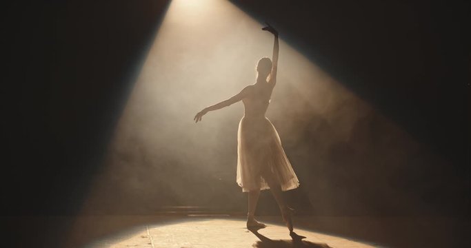 Female ballet dancer performing on theatre stage, dancing while spotted by bright light, isolated on black background - arts concept 4k footage