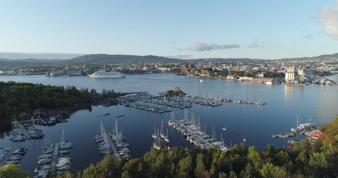 Cinema 4K drone shot with parallax motion of boat harbor on hovedøya, the main island in the Oslo fjord, with a backdrop of the downtown city in a sunset in Oslo, Norway.