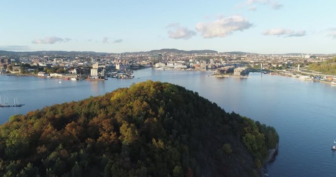 Cinema 4K drone shot with forward tilt reveal motion of Hoved&oslash;ya island, the blue Oslofjord and the Bj&oslash;rvika project with the Lambda Edvard Munch Museum and Opera House in autumn fall, in Oslo Norway.