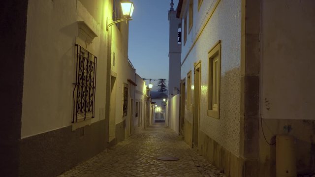 Old medieval street with public lamps during night at Tavira Portugal 4K