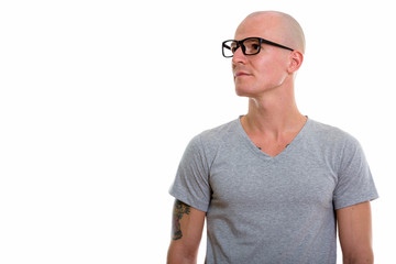 Studio shot of young handsome bald man wearing eyeglasses while