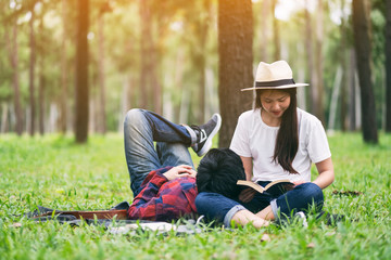 A young asian lover couple reading book and lying down together in the park