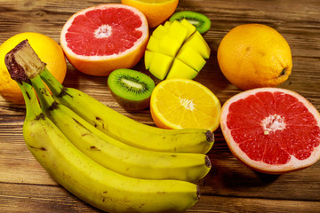 Assortment of tropical fruits on wooden table. Still life with bananas, mango, oranges, grapefruit and kiwi fruits