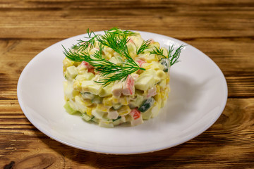 Salad with crab sticks, sweet corn, cucumber, eggs and mayonnaise on wooden table