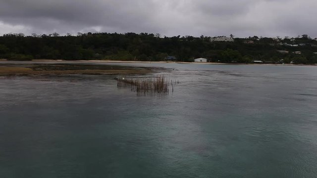 Aerial view of a fish trap set up in a large tropical lagoon near a Pacific Island village