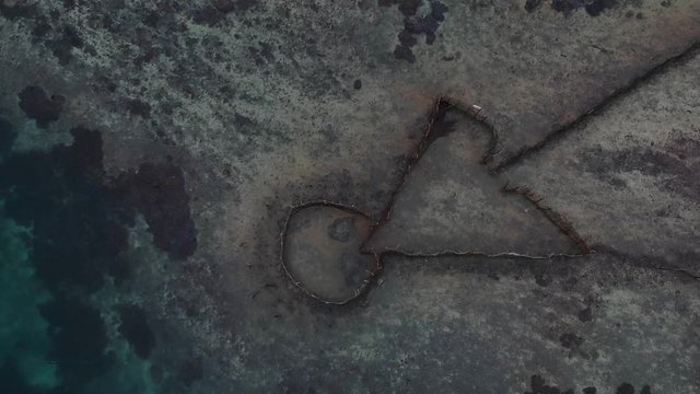 Aerial view of a fish trap set up in a large tropical lagoon near a Pacific Island village