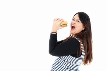 A young fat woman is eating a hamburger in her hand. She is smiling and happy to eat the food she likes. She is hungry. Healthy concept. Isolated on a white background.