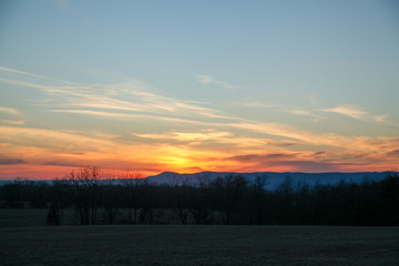 Obraz premium Sunrise over mountains with field in foreground