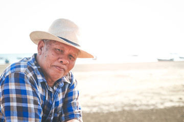 An elderly man wearing a hat to travel to the beach to relax, to live independently in retirement. Senior community concepts