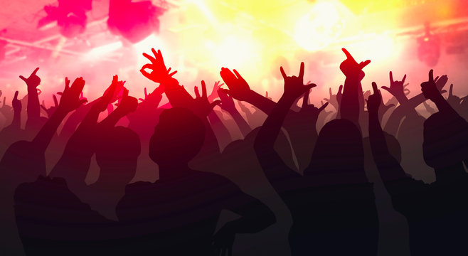 Silhouettes of concert crowd with hands raised at a music disco