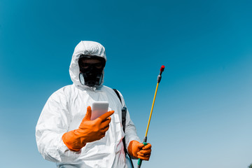 exterminator using smartphone while holding spray against sky