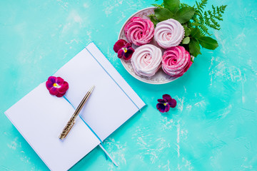 Flat lay with open book with empty pages,and pink meringues on concrete background. Overhead view, copy space. Blogger workplace.Sweet memories.Planning for future. Important thoughts.