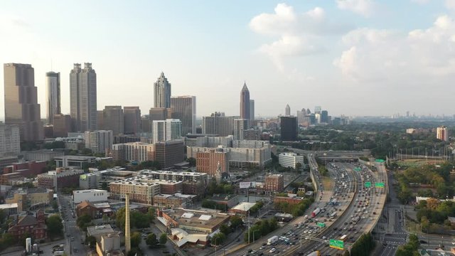 4K Ariel Drone Shot Over Skyline Buildings In Atlanta, Georgia. USA. Beautiful Tall Skyline Over Busy Highway Road With Cars Driving Through. Tall Buildings, Blue Cloudy Sky.