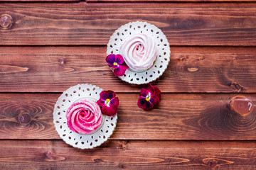 Colorful zephyr on wooden background.Set of homemade white and pink zephyr or marshmallow on wooden background. Marshmallow, Meringue, Zephyr, pansy.Tasty meringues.Copy space