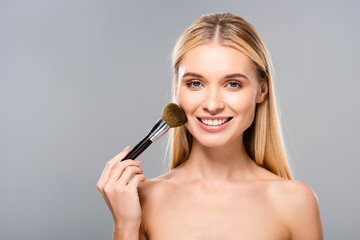 smiling young naked woman with cosmetic brush isolated on grey