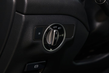 The dashboard of the car's interior is black with a dipped headlamp switch and side lights with a light sensor and automatic dimming and fog light button. Auto service industry.