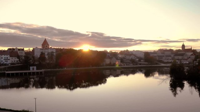 Aerial footage on the pond in the middle of the city, historic town in Poland, recreational path around the lake in the city, ancient buildings of the city, beautiful sunset in Warmia and Mazury
