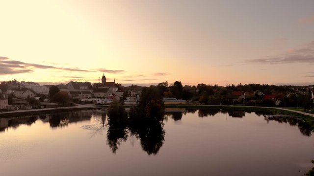 Aerial footage on the pond in the middle of the city, historic town in Poland, recreational path around the lake in the city, ancient buildings of the city, beautiful sunset in Warmia and Mazury