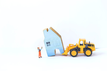 House moving business concept, construction concept, house insurance and maintenance, miniature worker guiding action with yellow truck moving miniature blue wooden house isolate on white background