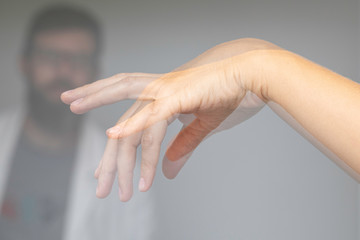 Doctor wathing shaking hand of a person suffering from Parkinson's disease