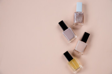collection of various nail polish bottle on beige background.Flat lay composition with cosmetic products. top view, Minimalistic style.fashion with beauty item. Nude colors.Copy space. Nails care