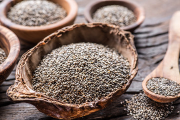 Chia seeds in different dishes on old wooden table.