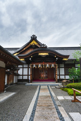 A beautiful traditional house or building within the Fushimi Inari Taisha shrine complex on a cloudy summer day. 