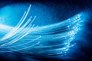 Bundle of optical fibers with lights in the ends. Blue background.