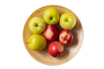 Apples on a plate. Fresh organic red and yellow apples on a wooden plate, close up, isolated on white background, top view