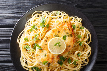 Tasty classic chicken Francaise with spaghetti in lemon wine sauce close-up on a plate. Horizontal...