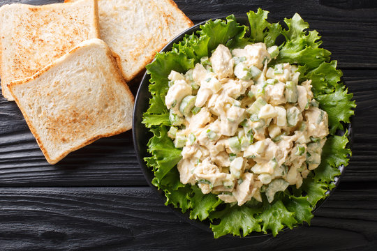 Organic chicken salad with celery, eggs seasoned with sauce closeup on a plate. Horizontal top view