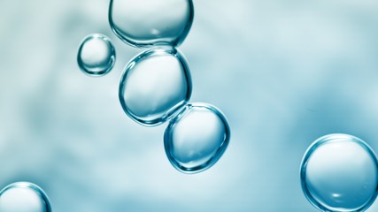 transparent gas bubbles on water surface. Worms-eye low angle with crystal bubbles in purified water on blue background. cosmetic background with copy space