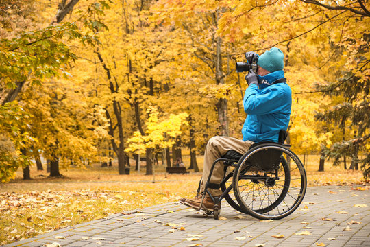 person with a disability  taking pictures, disabled photographer in yellow autumn park 