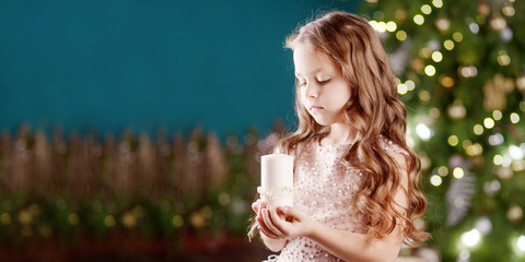 Portrait of a smiling long-haired little girl in dress on background of  lights. Little girl talking on the phone. Christmas, New Year and birthday celebration concept. Winter holidays. Copy space
