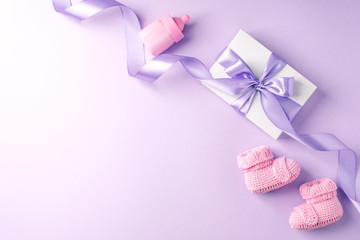 Pair of small baby socks and gift box on lilac background with copy space for your warm message,...