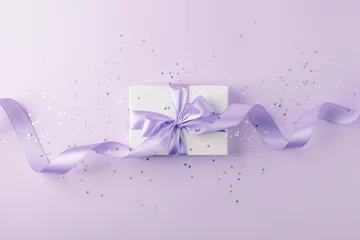 Poster Craft gift box on a lilac background, decorated with a textured bow and feathers, creating a romantic luxury atmosphere. For birthday, anniversary presents, gift post cards. © misskaterina